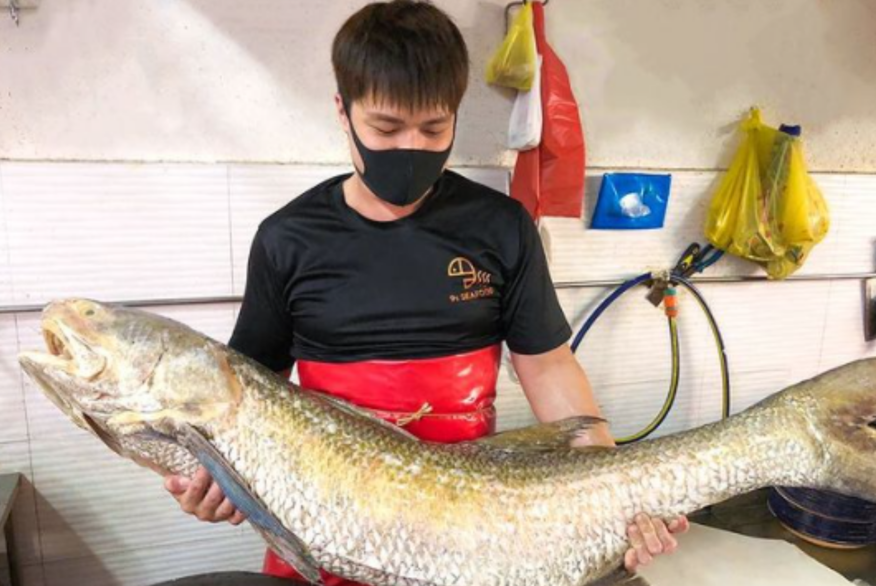 A 9s Seafood staff holding a humongous fish!